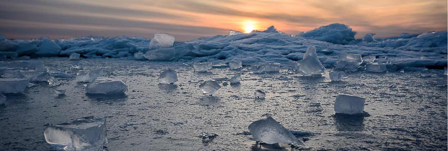Abstract frozen winter sunrise seascape with ice and colored the sky